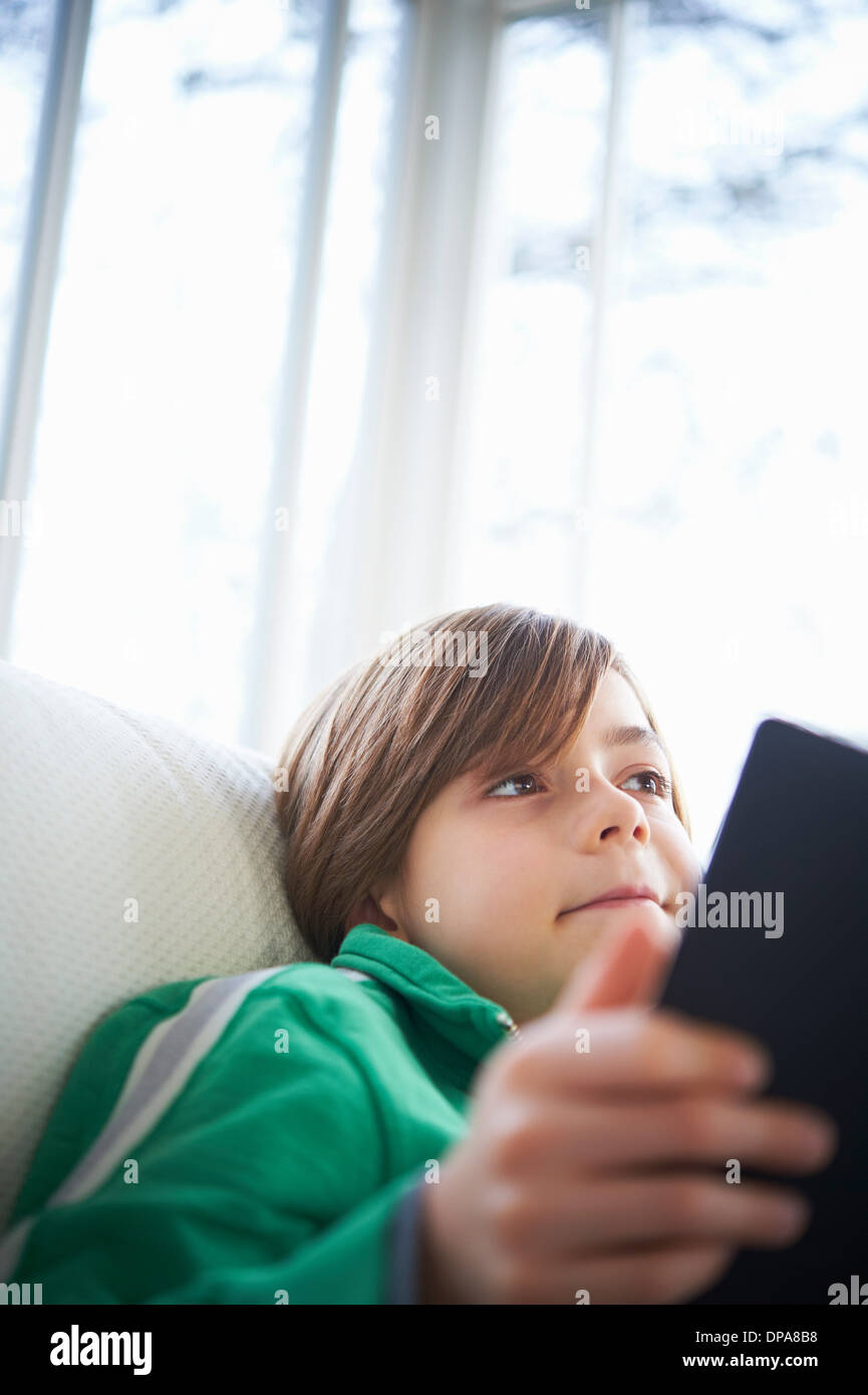 Boy on sofa using digital tablet Stock Photo
