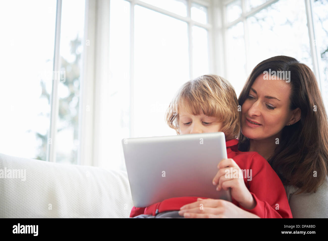 Mother and son on sofa using digital tablet Stock Photo