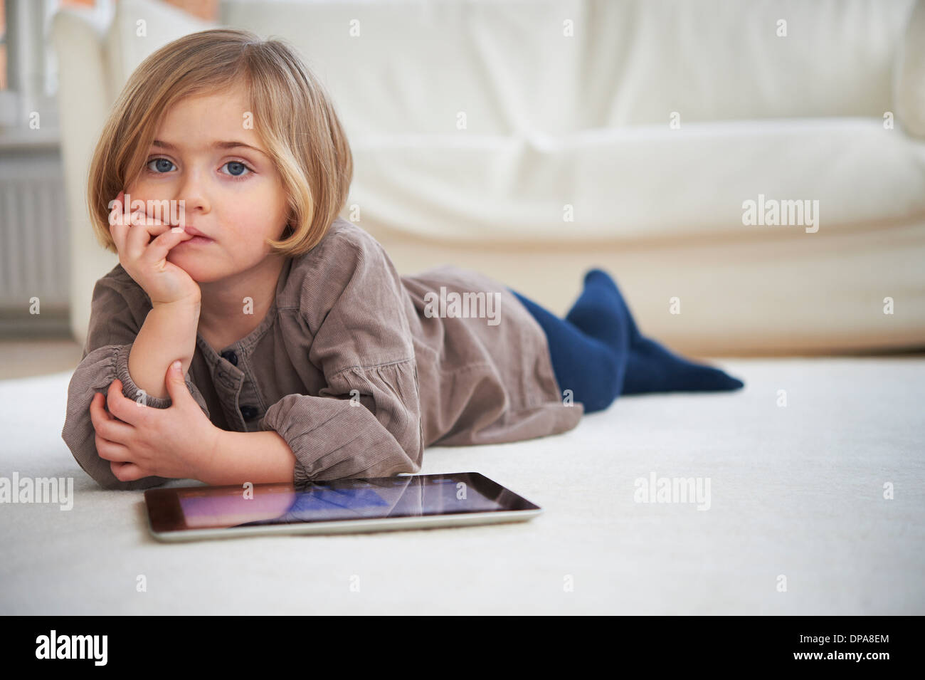 Girl lying on floor using digital tablet Stock Photo