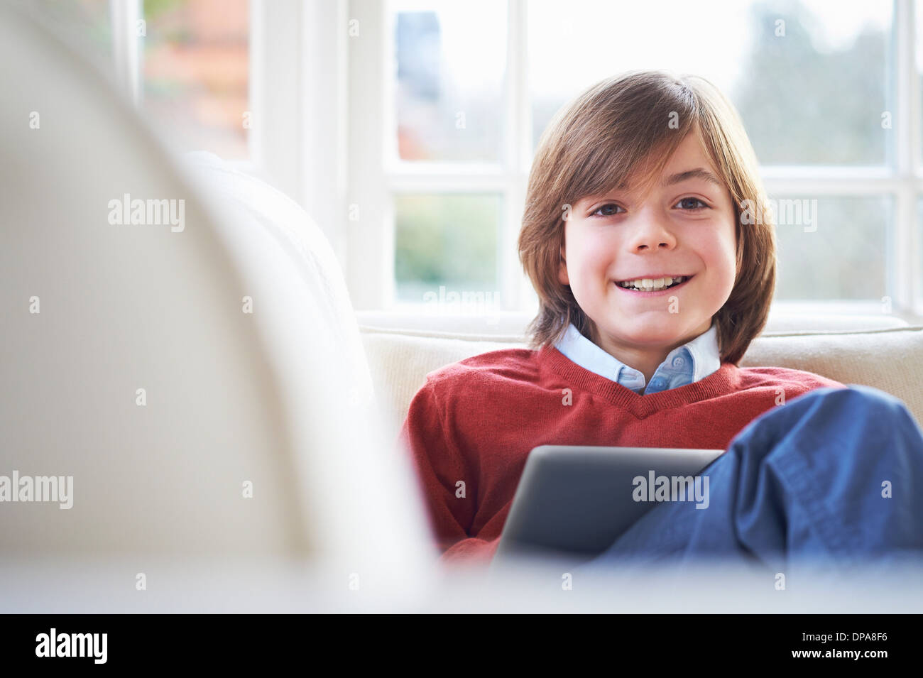 Boy on sofa using digital tablet Stock Photo