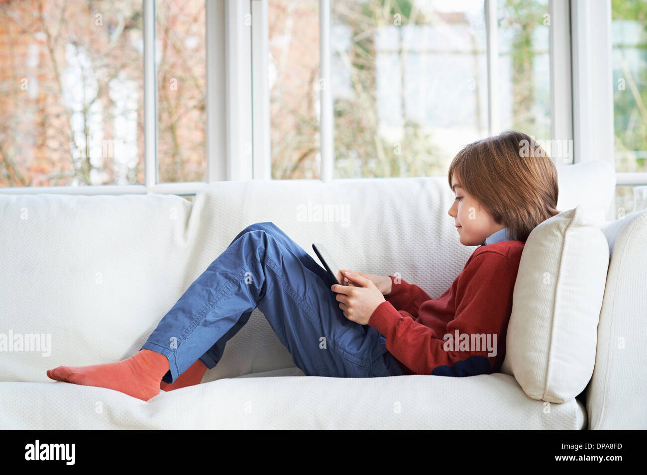 Boy on sofa using digital tablet Stock Photo