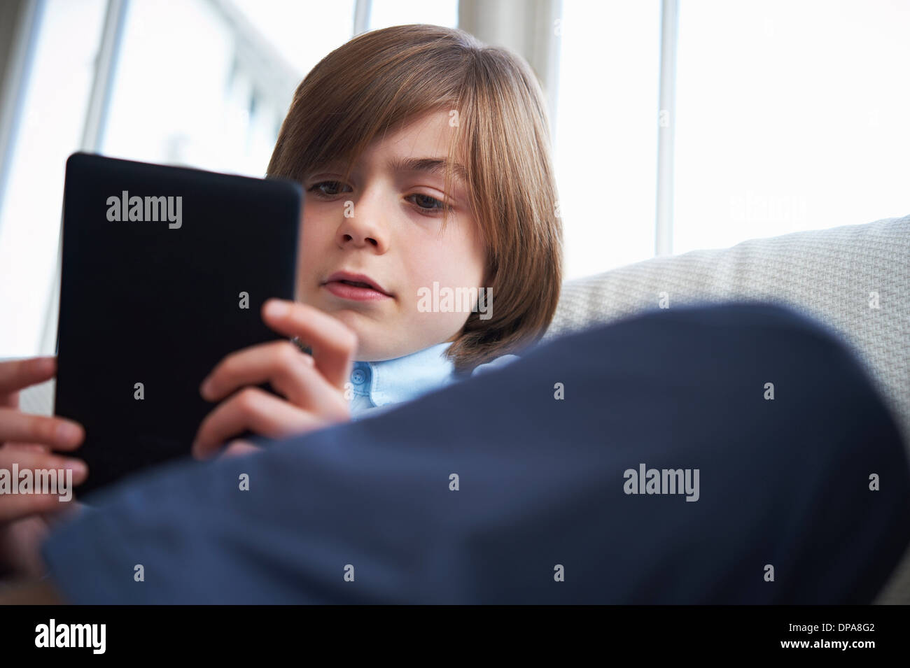 Boy on sofa using digital tablet Stock Photo