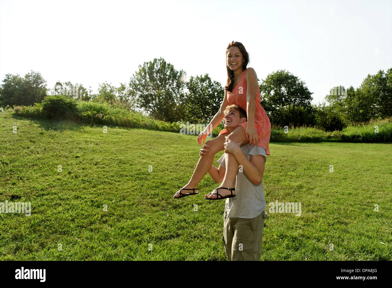 Young woman sitting on young mans shoulders Stock Photo
