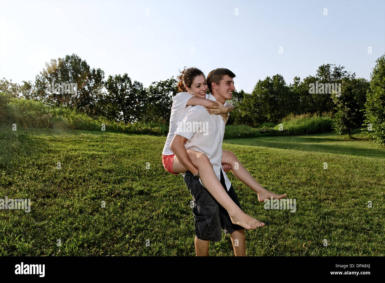 Young man giving piggyback ride to young woman Stock Photo