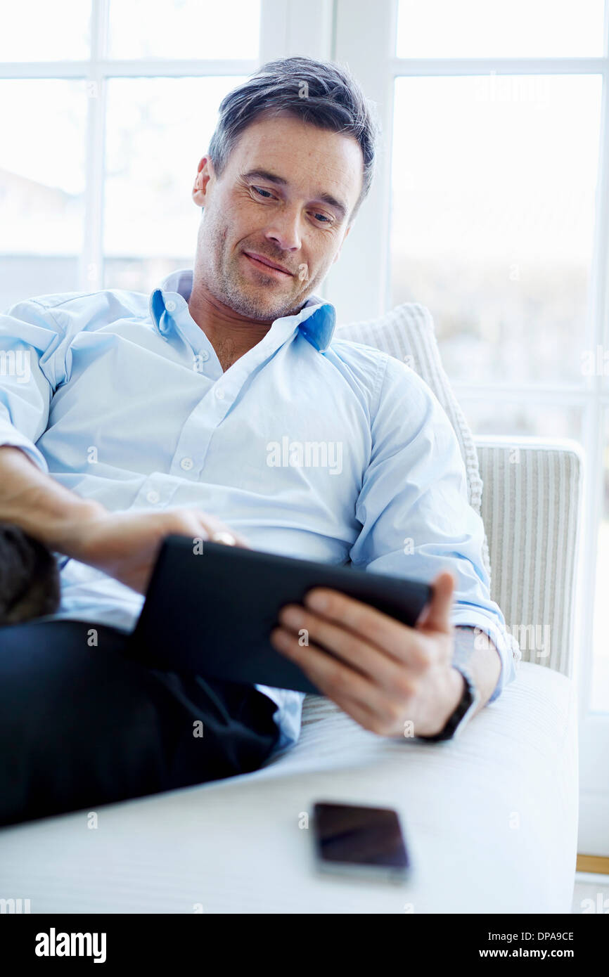 Man sitting on sofa using digital tablet Stock Photo