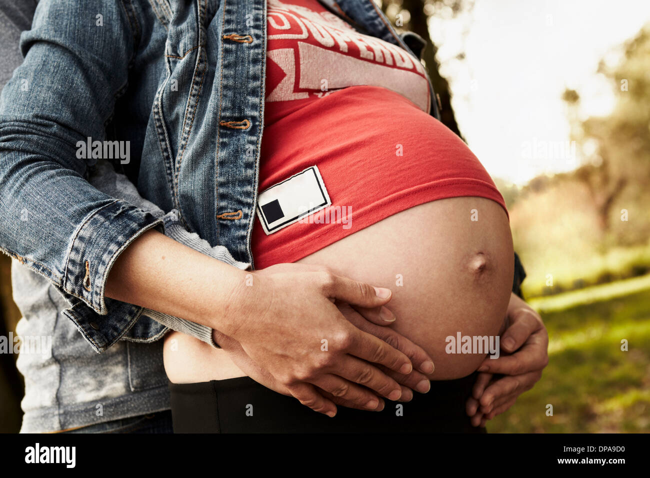 Midsection of pregnant woman and partner holding bump Stock Photo