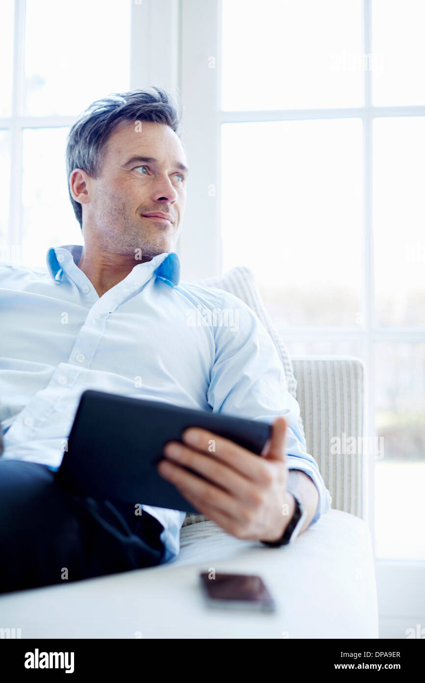 Man sitting on sofa using digital tablet Stock Photo