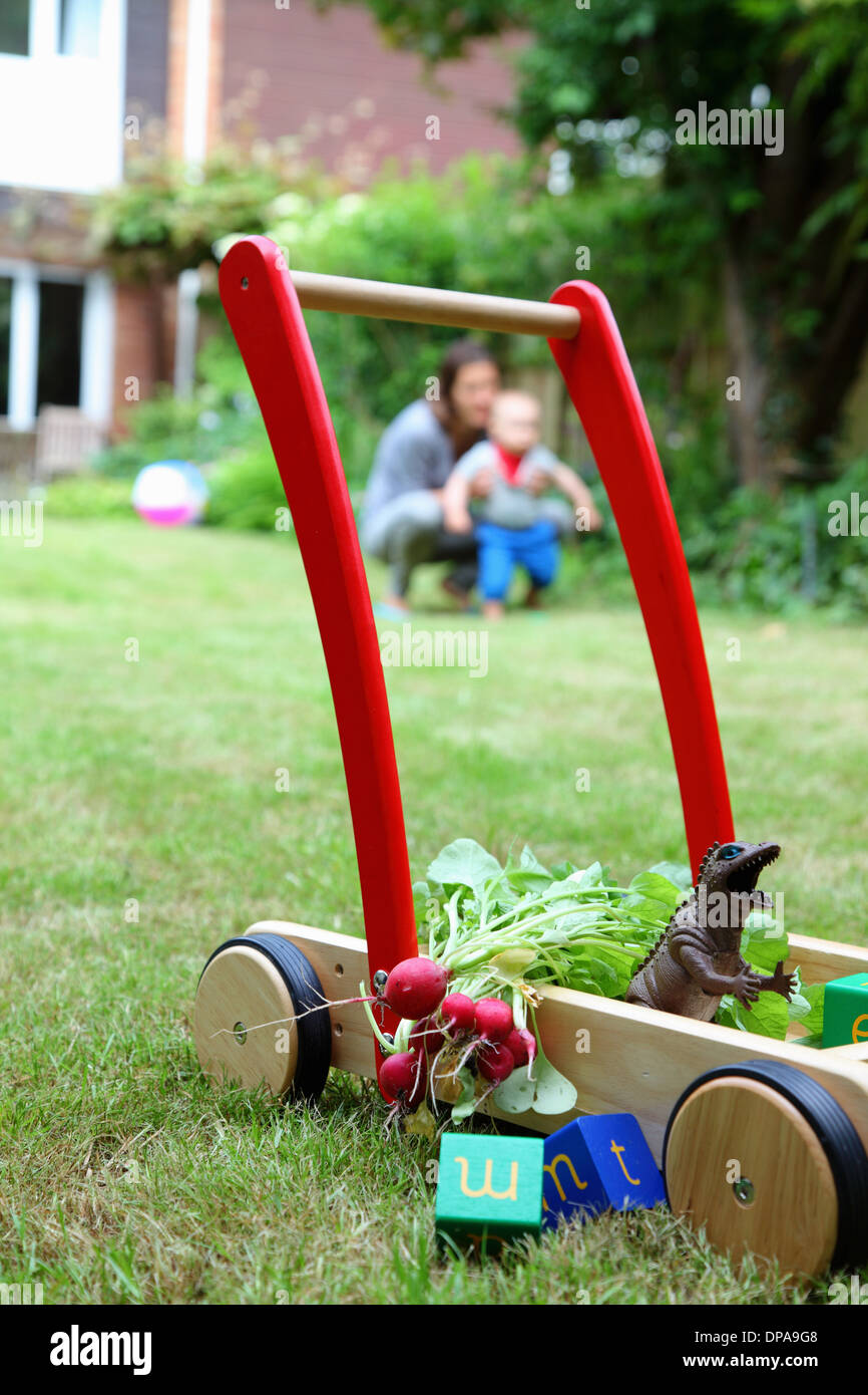 Mother and child with push cart and toys in garden Stock Photo Alamy
