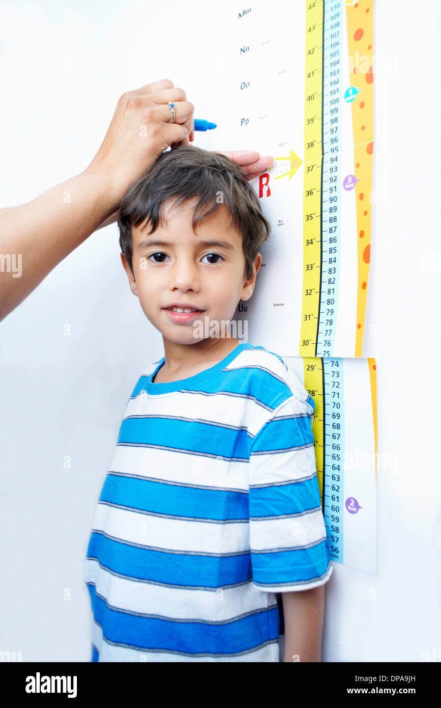 Boy standing against height chart being measured Stock Photo