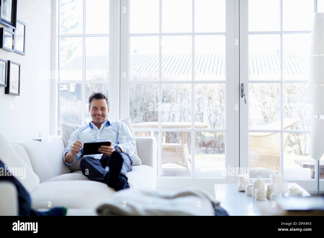 Man relaxing on sofa using digital tablet Stock Photo