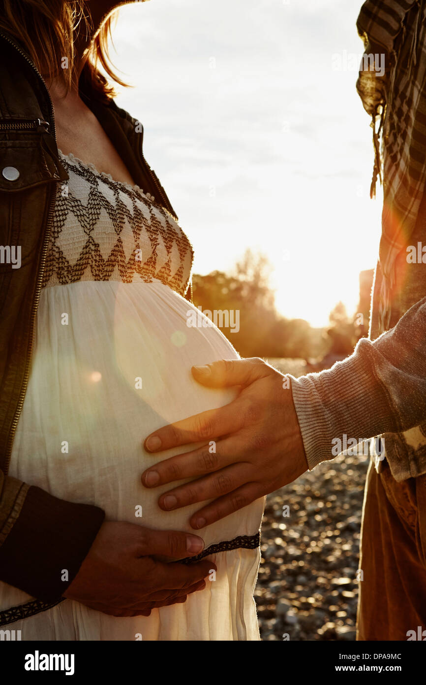 Midsection of pregnant woman and partner touching bump Stock Photo