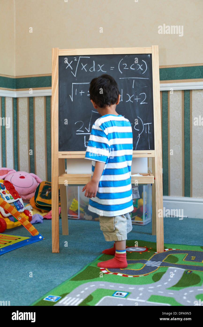 Boy standing beside blackboard with algebra Stock Photo
