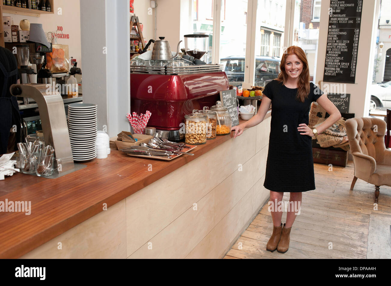 Portrait of young woman standing at cafe counter Stock Photo