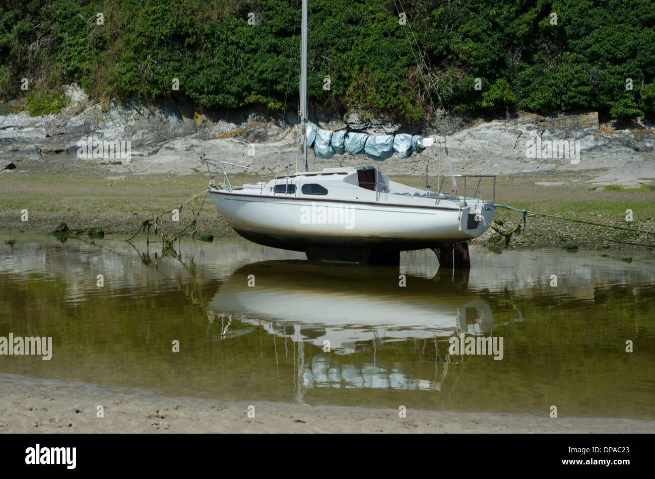 A small yacht sitting in the sand while the tide is out in Newquay Stock Photo