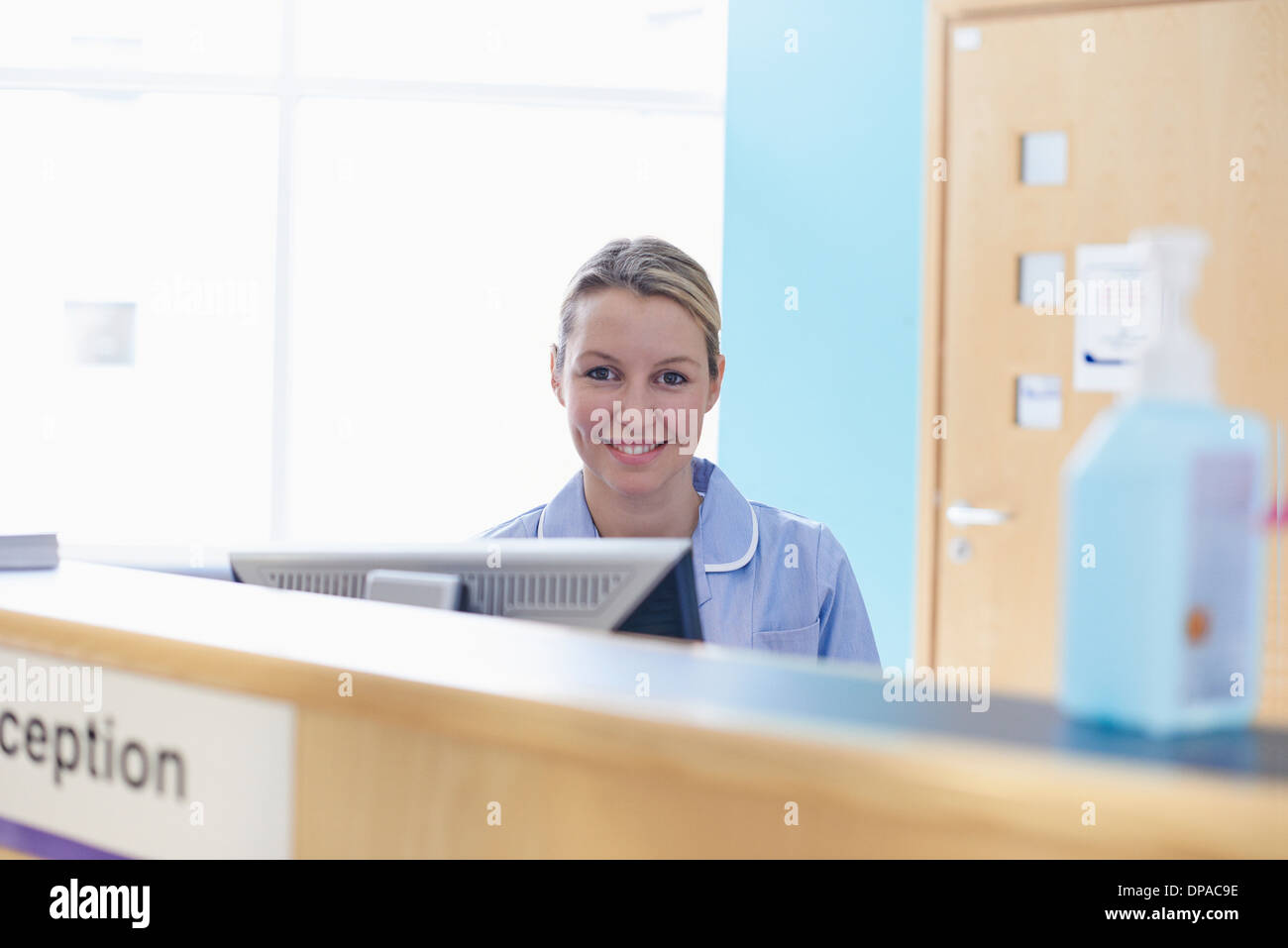 Nurse sitting at reception desk Stock Photo Alamy
