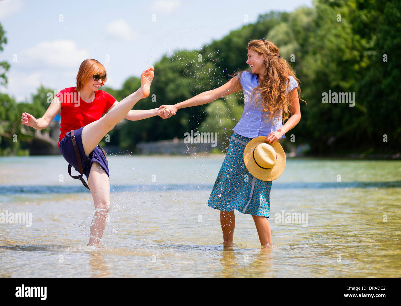 Two female friends playing in Isar River, Munich, Germany Stock Photo
