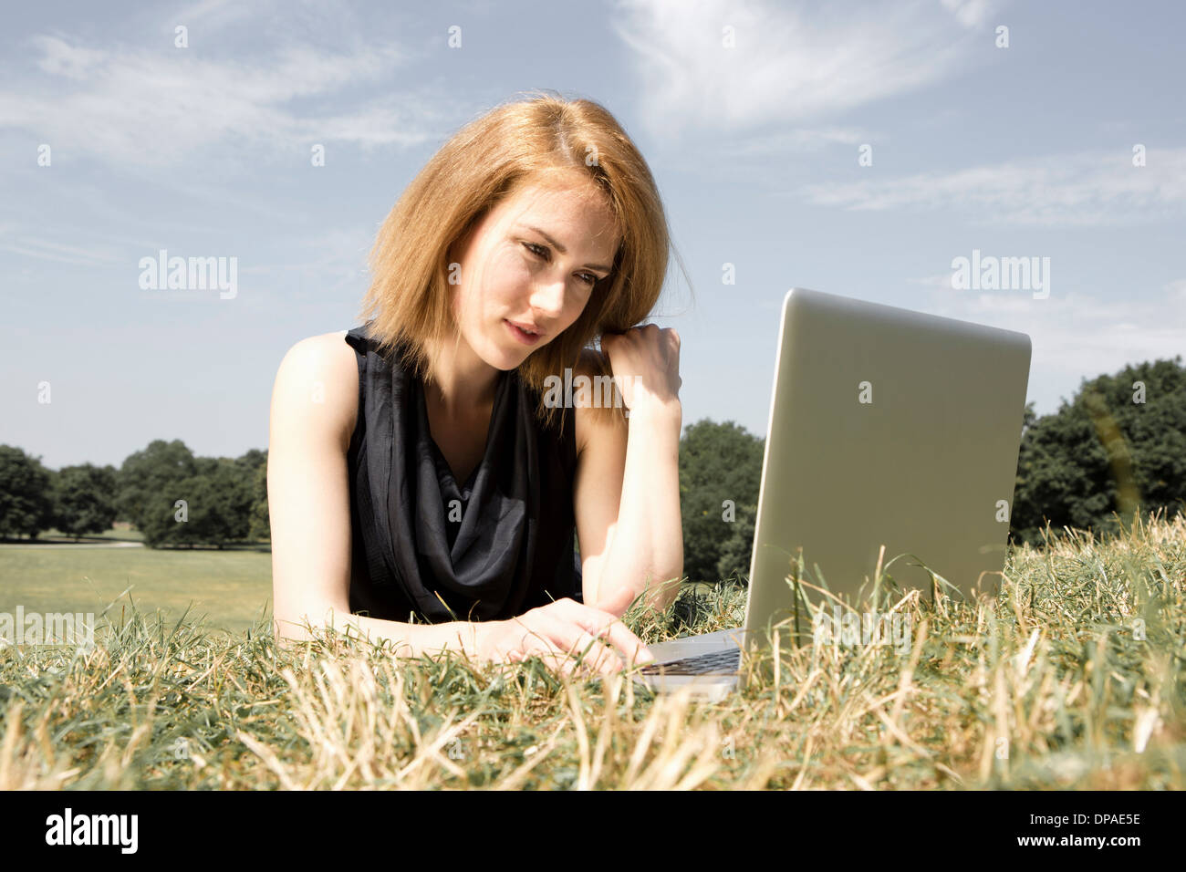 Young woman using laptop in park Stock Photo