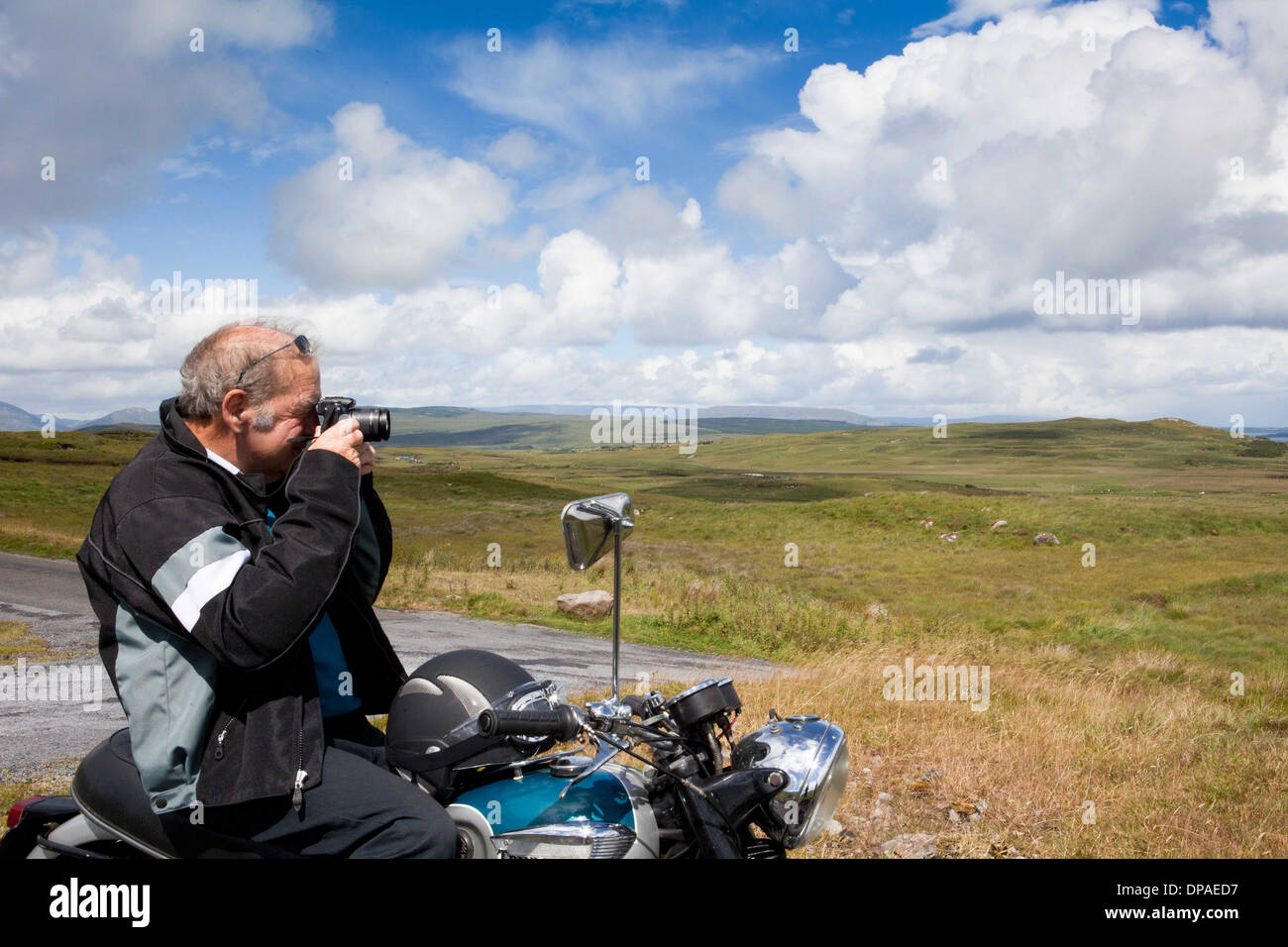 Senior male motorcyclist taking a photograph of scene Stock Photo