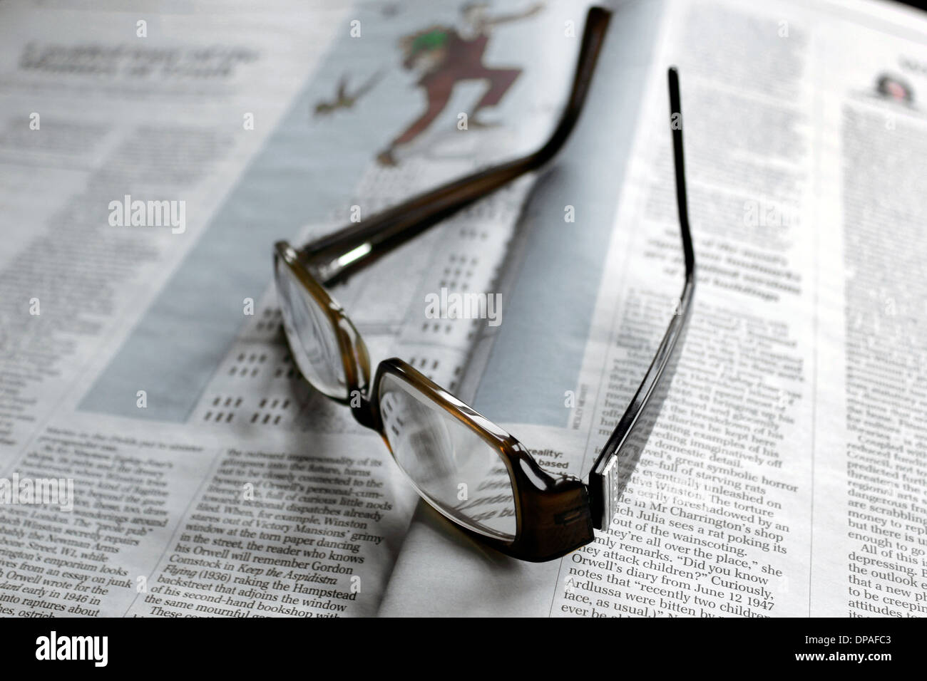 Reading spectacles placed on open article Stock Photo