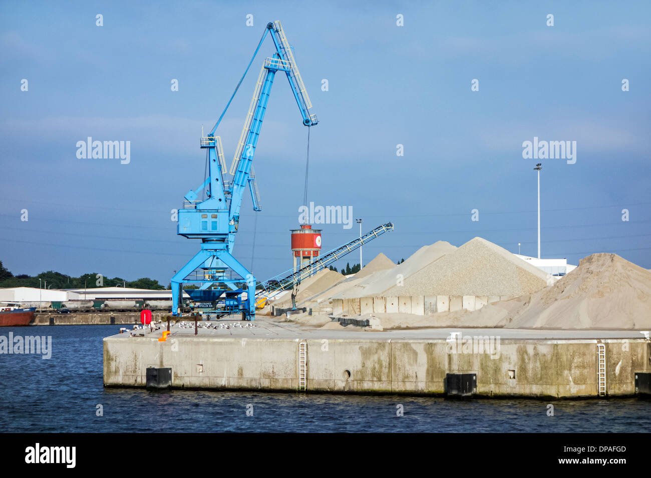 Dock crane and heaps of sand at the Ch. Kesteleyn gravel terminal in the port of Ghent, East Flanders, Belgium Stock Photo