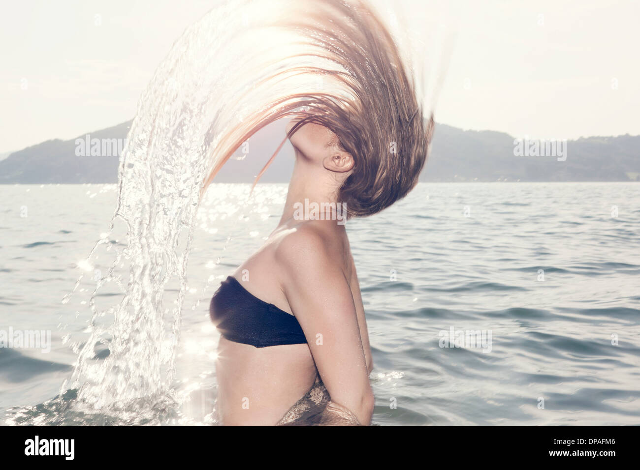 Young woman in sea throwing head back Stock Photo