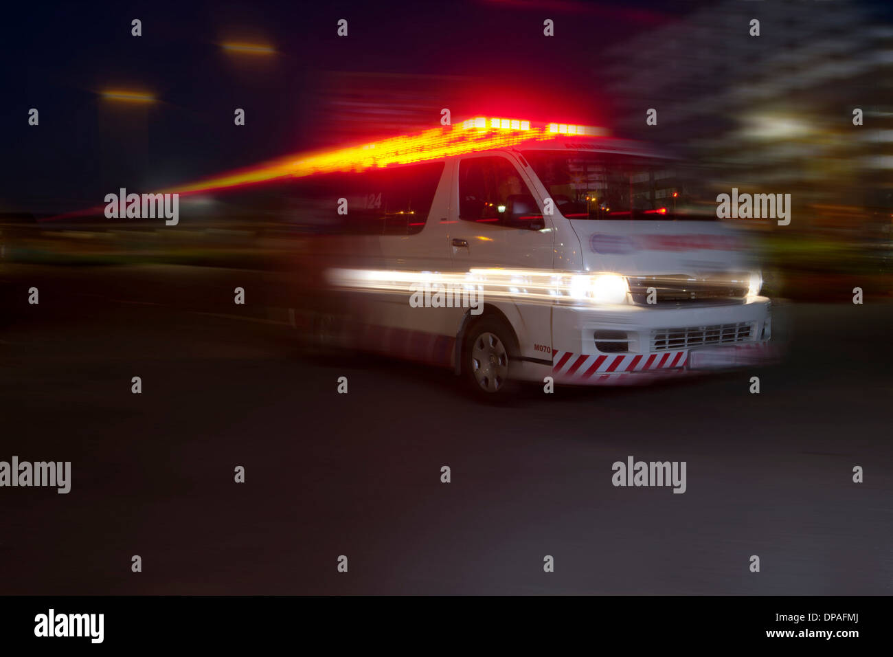 Emergency ambulance speeding through city at night Stock Photo