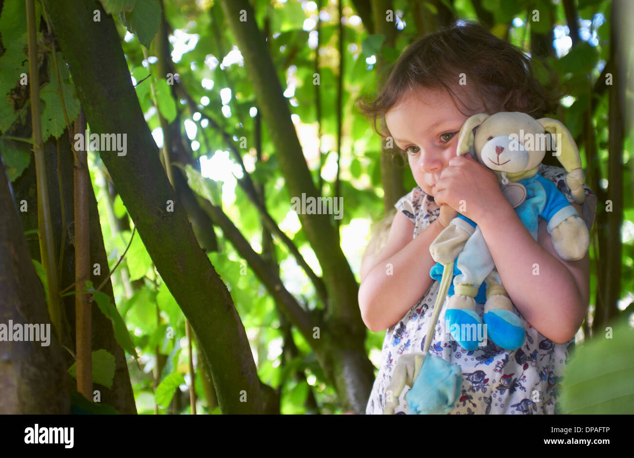 Portrait of female toddler with cuddly toy in woods Stock Photo