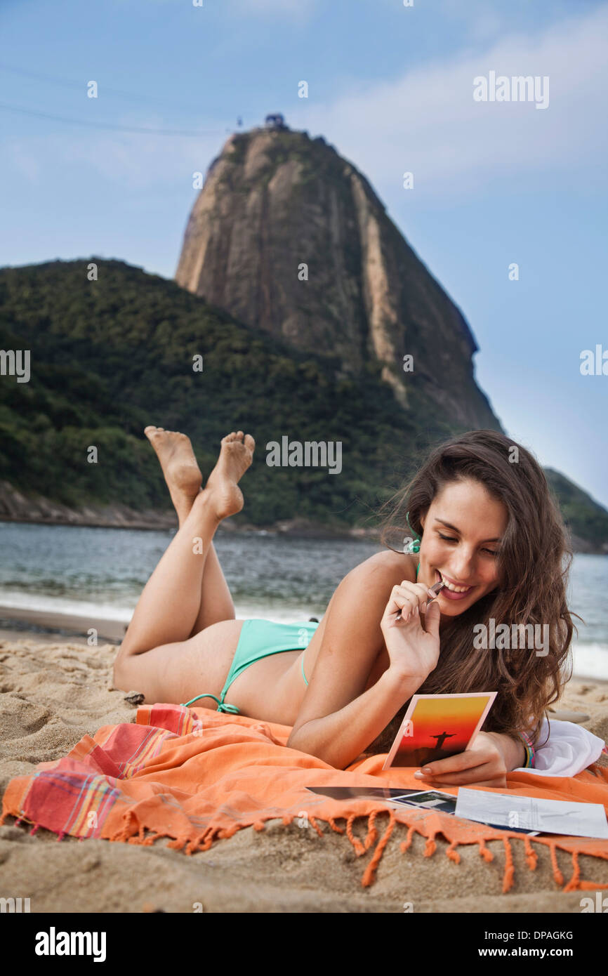 Woman on beach writing postcard, Rio de Janeiro, Brazil Stock Photo