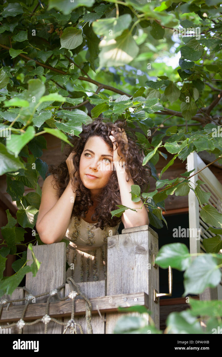 Woman peering out of tree house Stock Photo