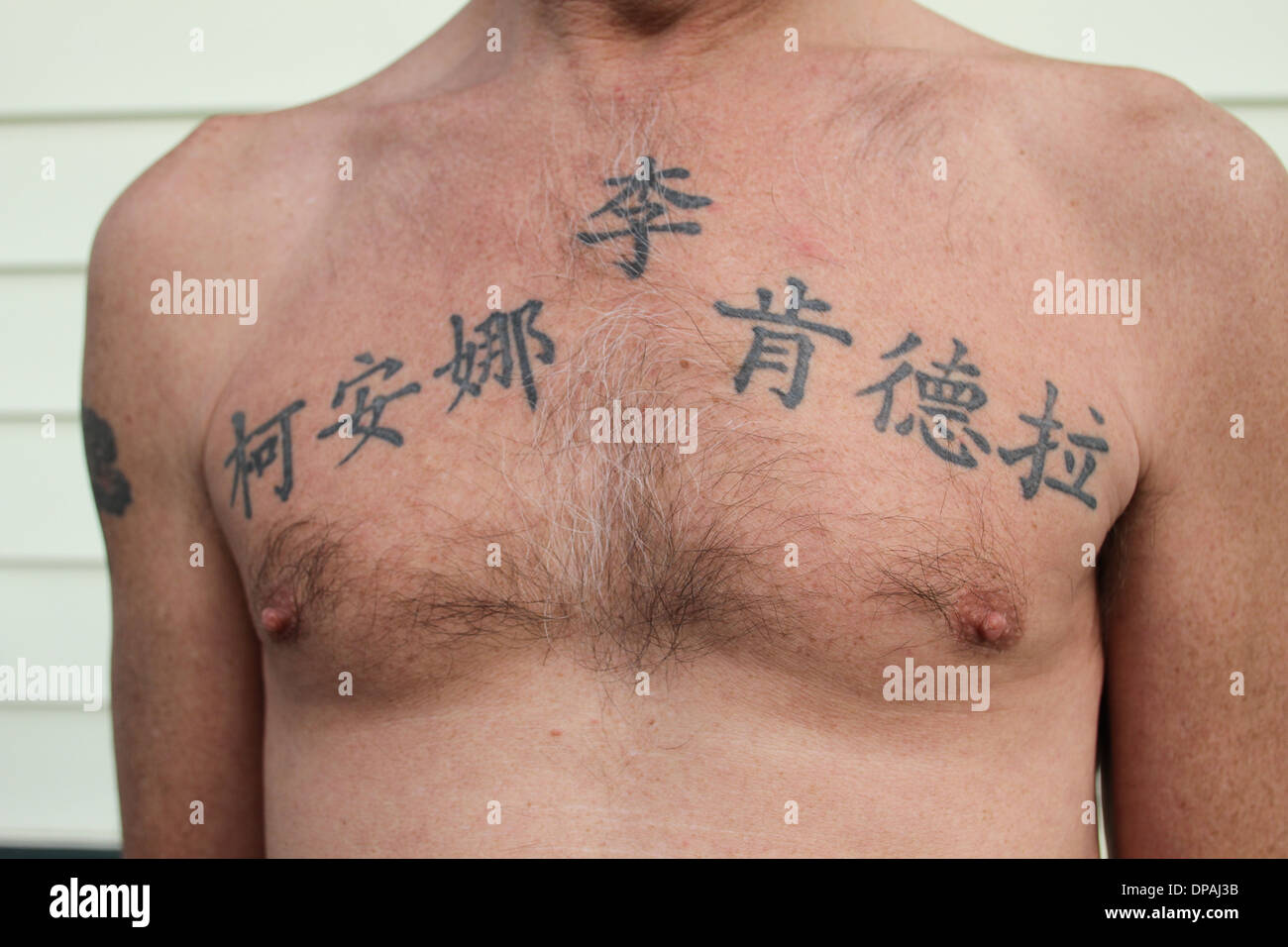 A man tattooed with his kids names in Chinese on his chest Stock Photo