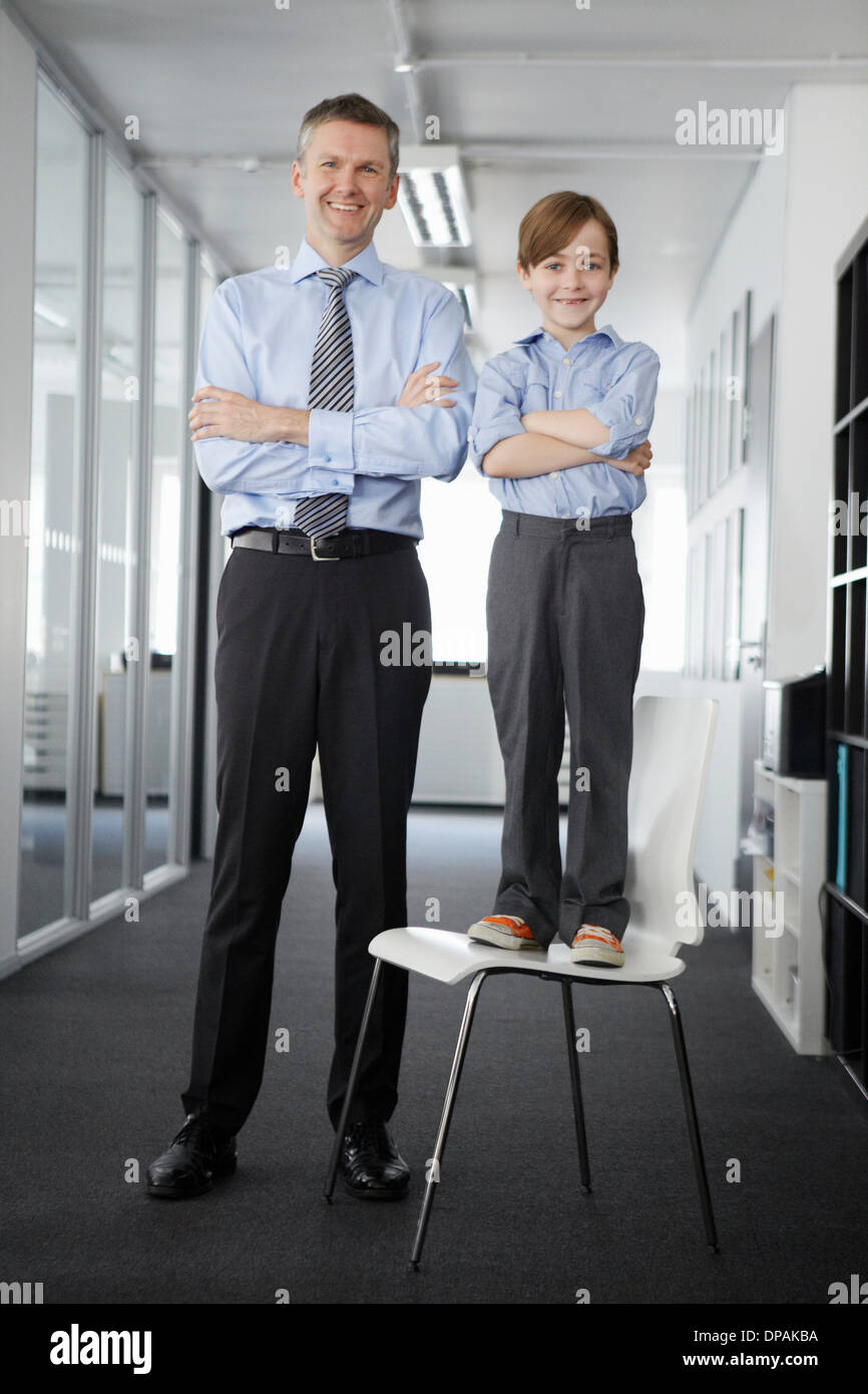 Father and son in office, boy standing on chair Stock Photo