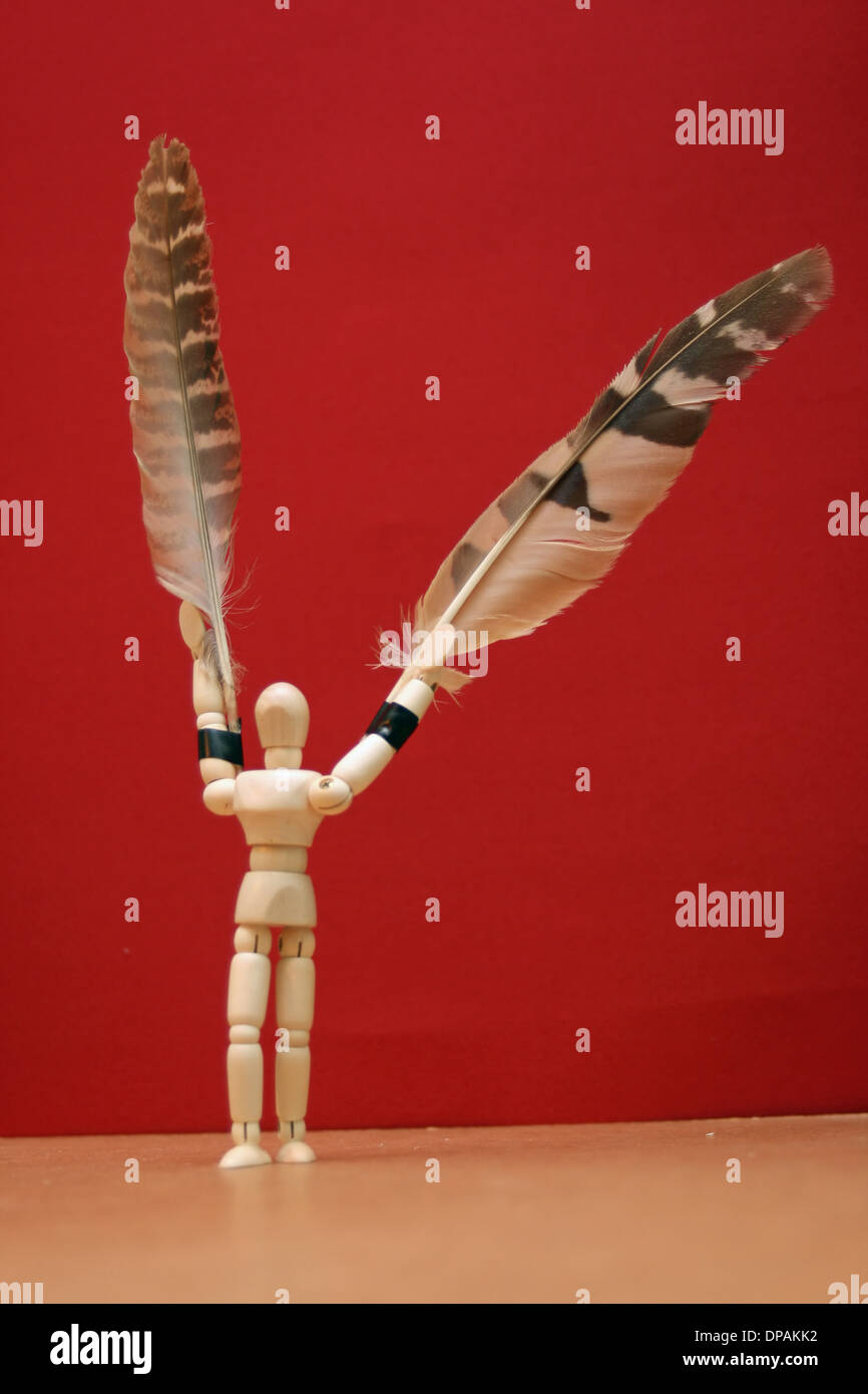 concept of a 'bird man' with a artists' manikin with feathers on his arms. Stock Photo