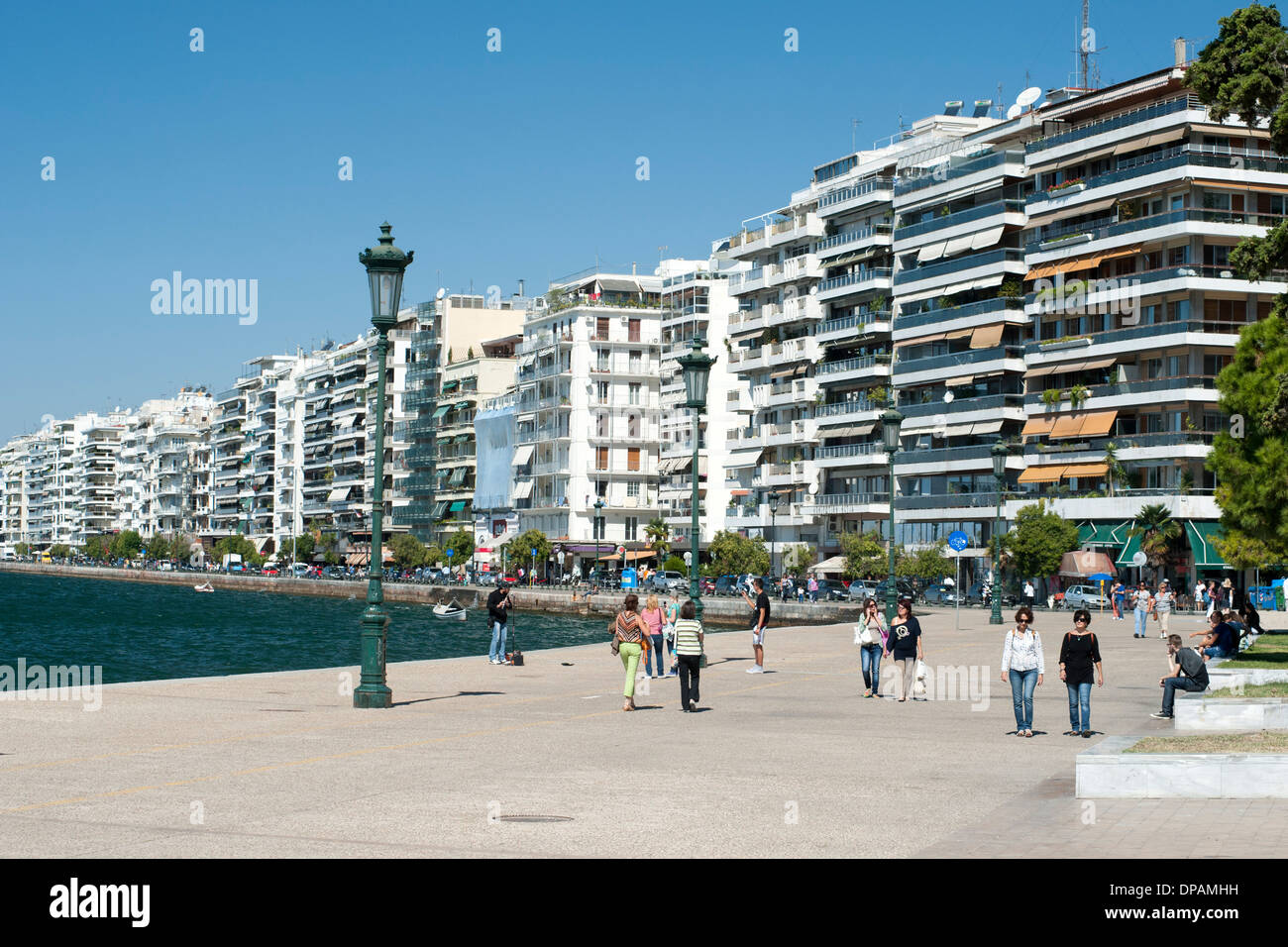 View of buildings on Nikis Avenue and pedestrians strolling on the waterfront in Thessaloniki, Greece. Stock Photo