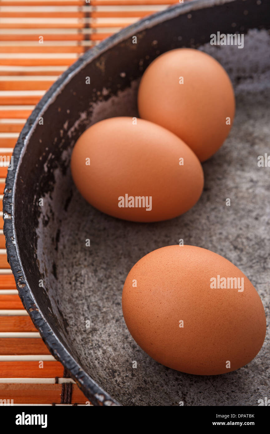 three brown eggs on an old pan Stock Photo