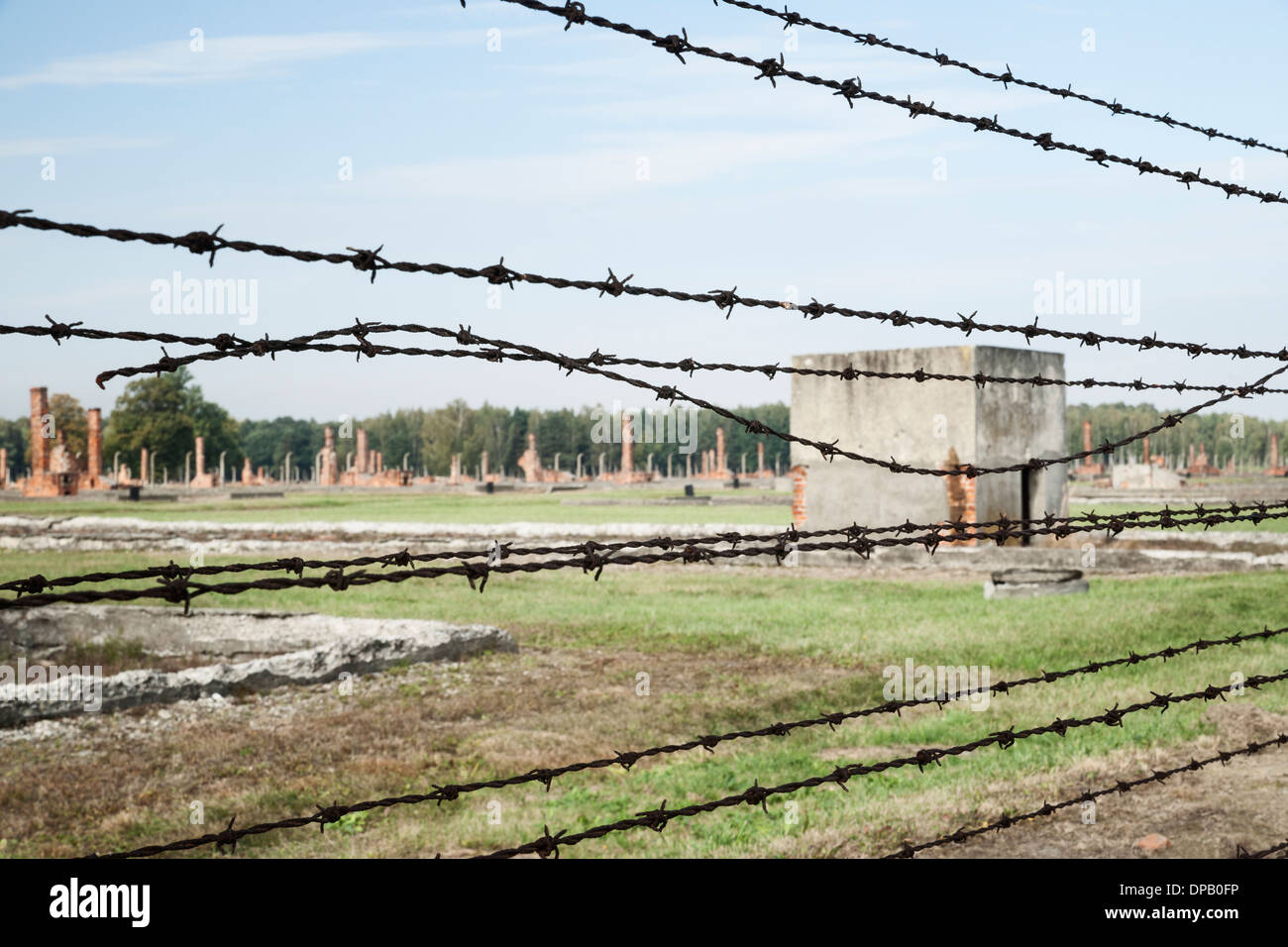 Barbed wire fence and ruins of former barrack housing, Auschwitz II Birkenau concentration camp Stock Photo