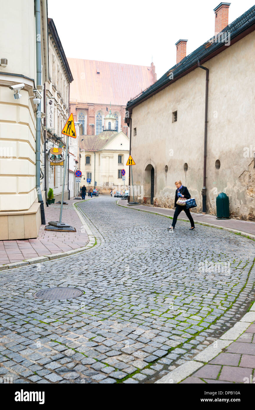Woman crossing cobblestone street in Old Town, Krakow, Poland, Europe Stock Photo