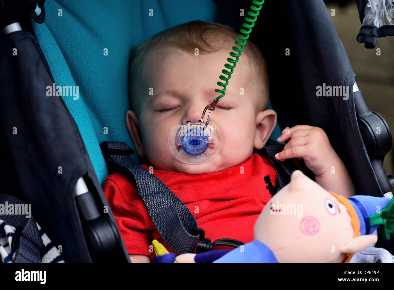 Baby asleep in a pram sucking on a dummy Stock Photo Alamy