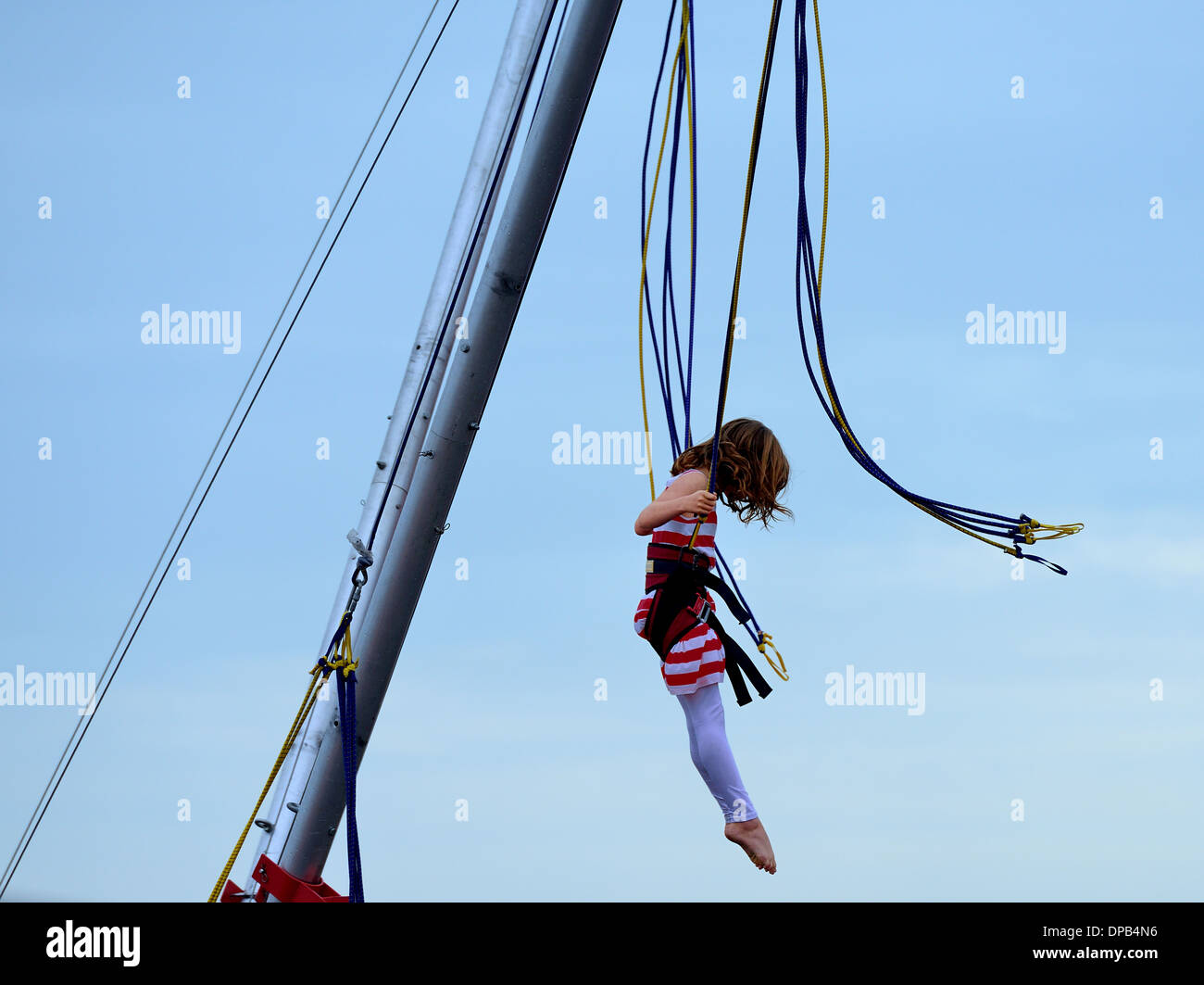 Young girl in a harness bouncing at a fun fair, Clacton Essex UK Stock Photo