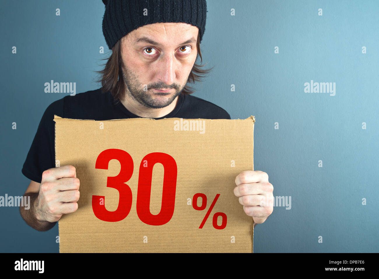 Man holding cardboard paper with thirty percent sales discount price. Consumerism concept, retail store promotion. Stock Photo