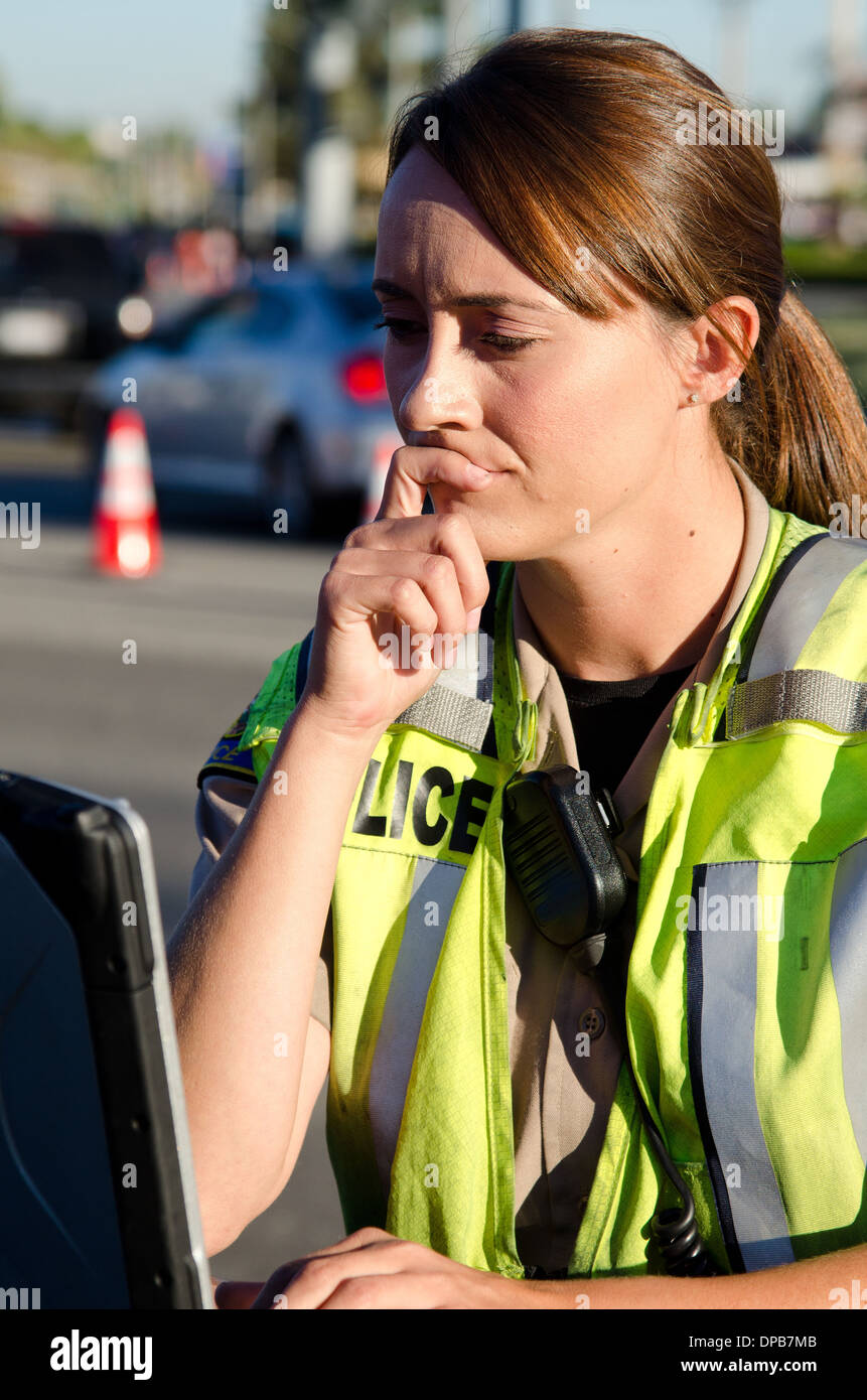 a female police officer types on her lap top computer while on a call ...