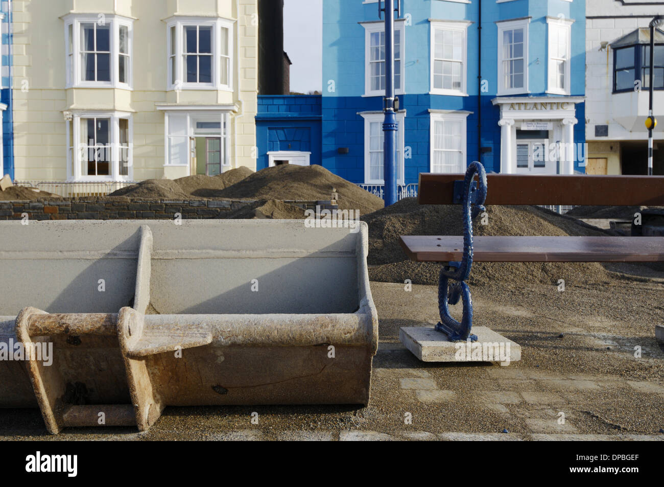 Aberystwyth, Wales, UK. 10th January 2014. A week after a severe storm surge and gale force winds damaged Aberystwyth's promenade, debris is still strewn around the area. Council workers grade flood deposits with machinery to seperate sand and paving slabs. Work begins dismantling the Grade 2 listed public shelter, the foundations of which were undermined by the sea. Credit:  keith burdett/Alamy Live News Stock Photo