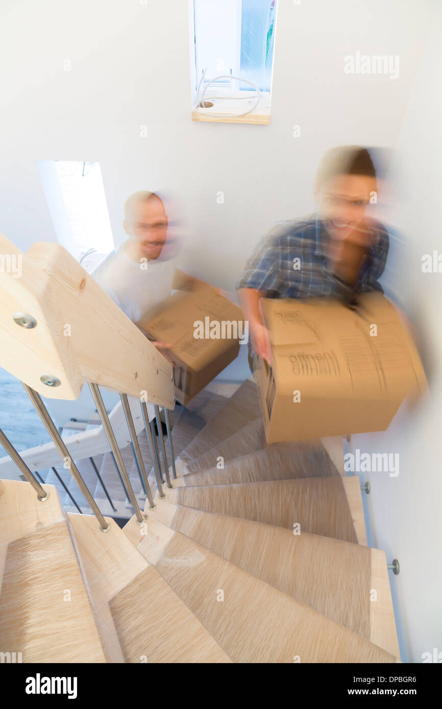 Young couple moving into new home, carrying cardboard boxes Stock Photo ...