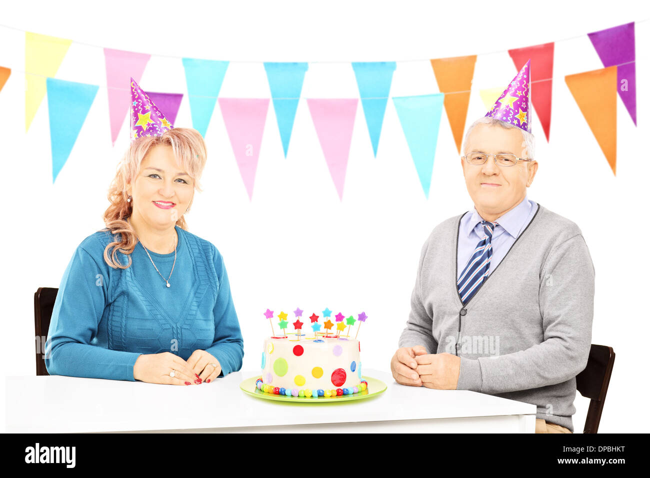 Senior couple sitting on table with big cake and celebrating birthday Stock Photo