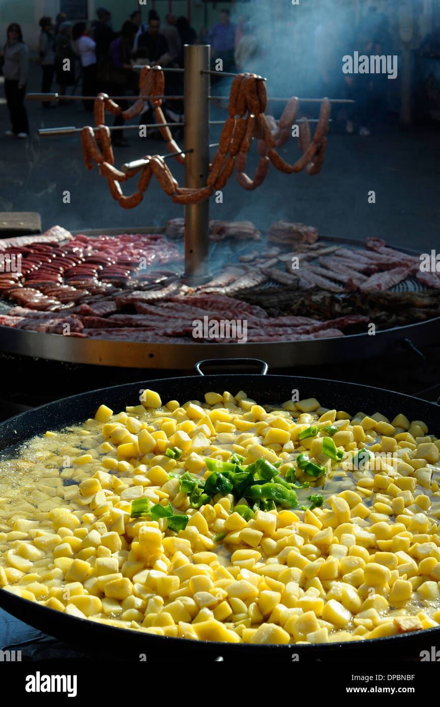 large pan containing potato stew in front of giant barbecue in the annual All Saints Market in Cocentaina, Spain Stock Photo