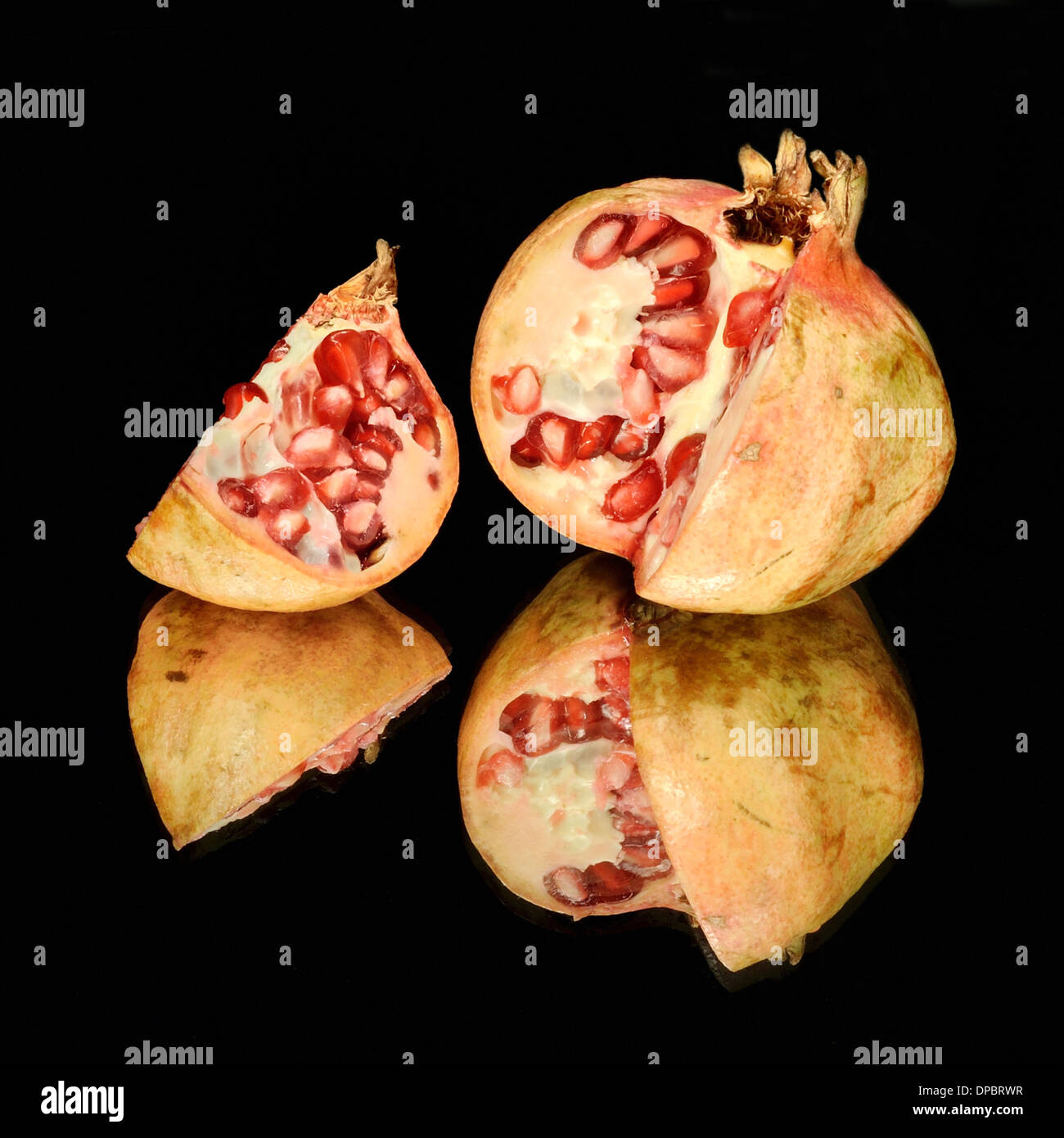 Pomegranate cut on mirror with black background. Stock Photo