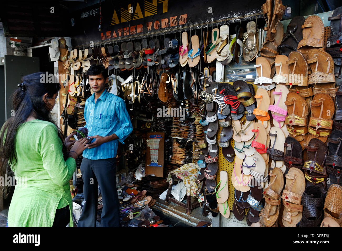 A young woman buying leather sandals from a street seller in Bombay India Stock Photo