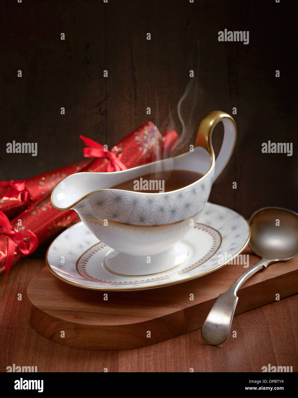 Rich gravy served in gravy boat with ladle and Christmas crackers Stock Photo