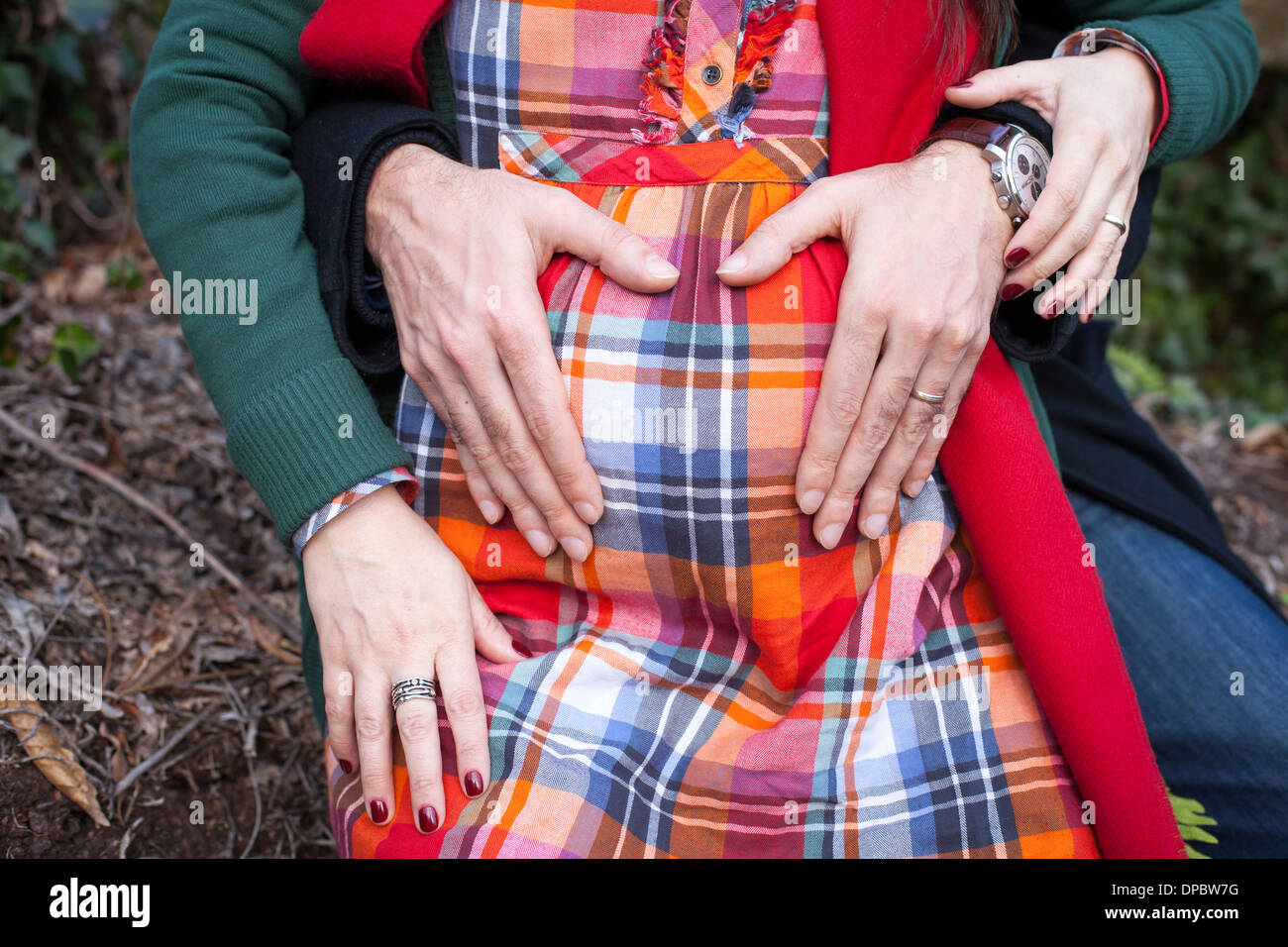 Hands of mother and father on baby belly forming a heart. Stock Photo