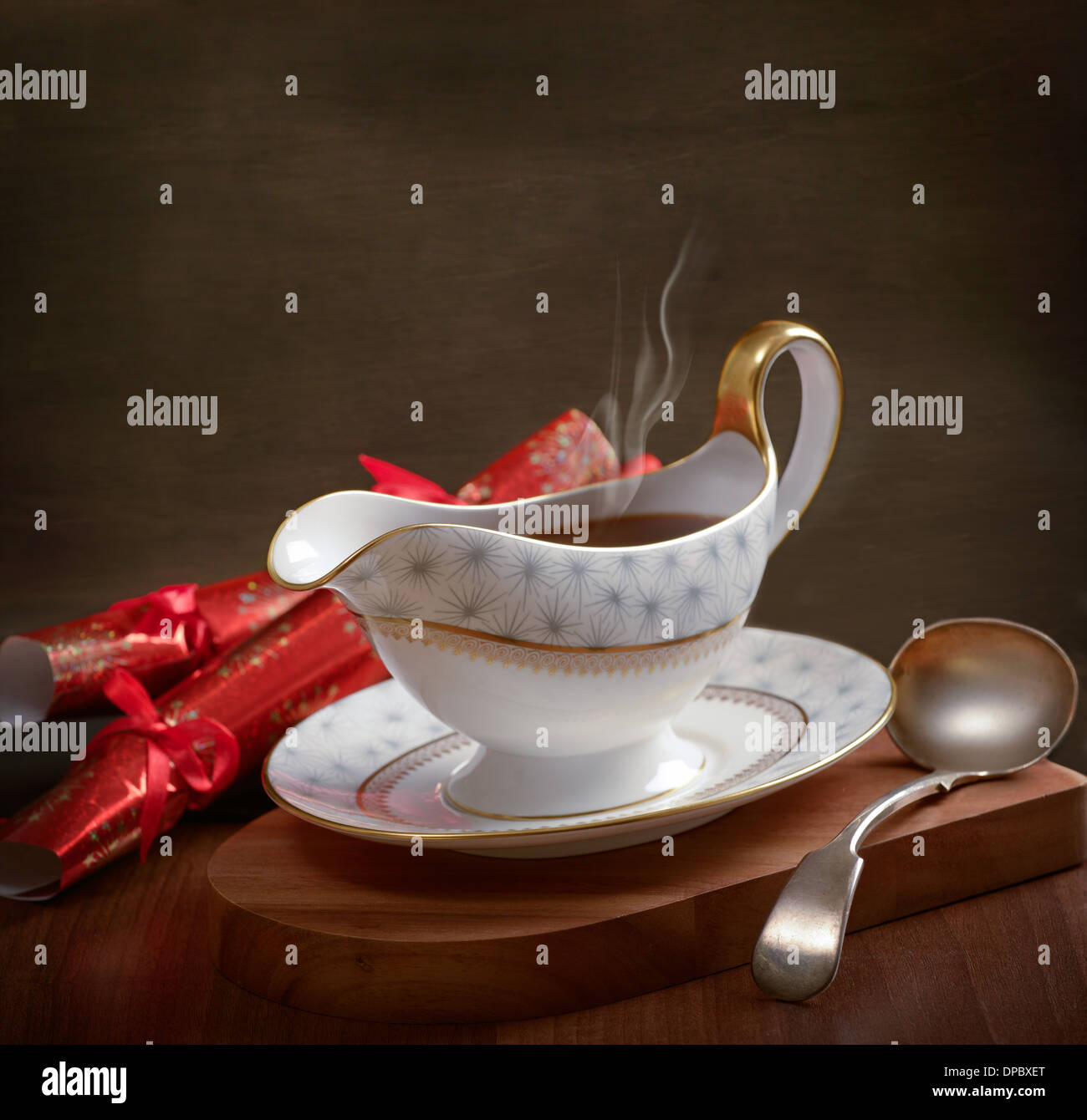 Rich gravy served in gravy boat with ladle and Christmas crackers Stock Photo