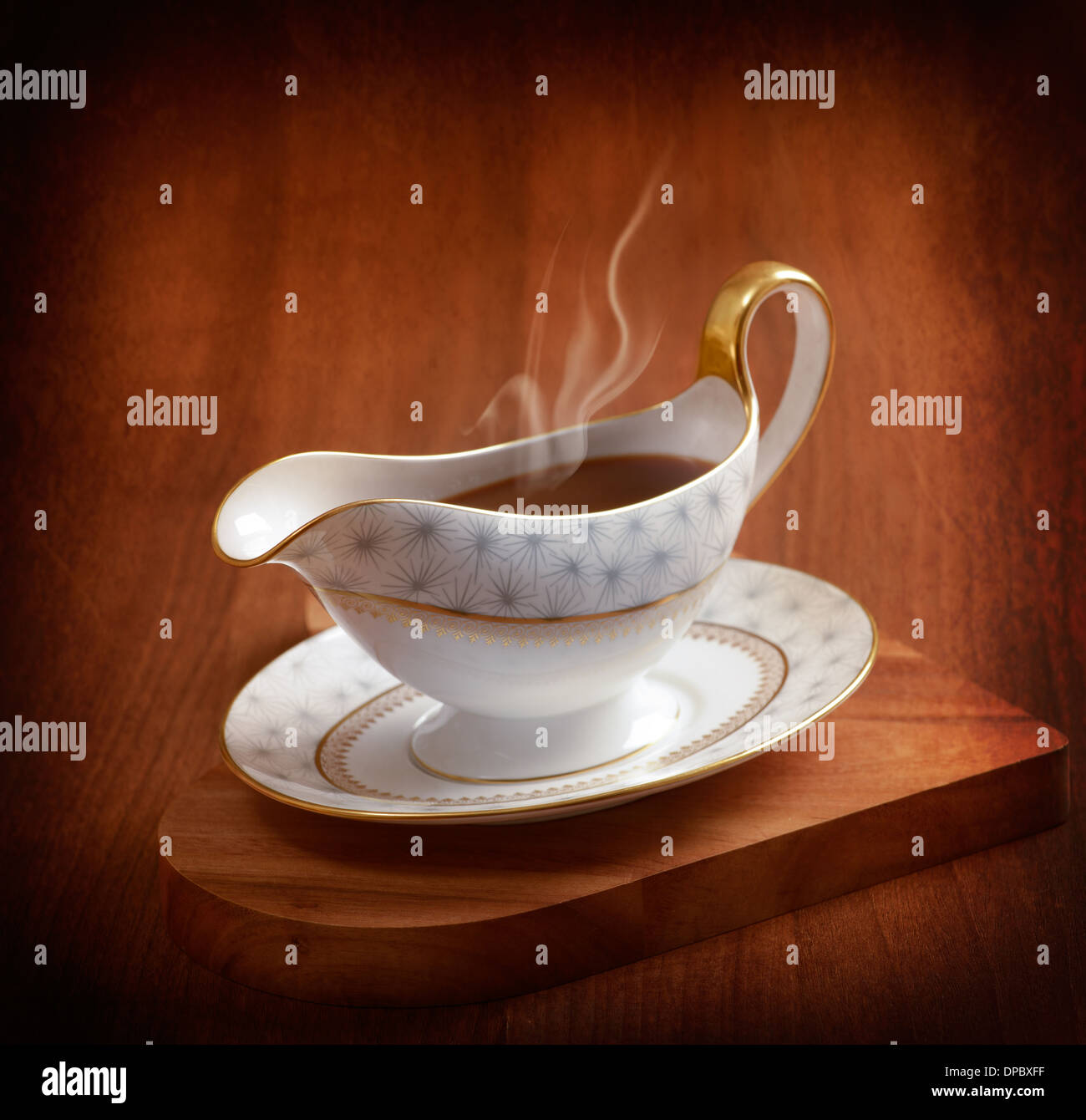 Rich steaming gravy served in gravy boat on wooden board Stock Photo